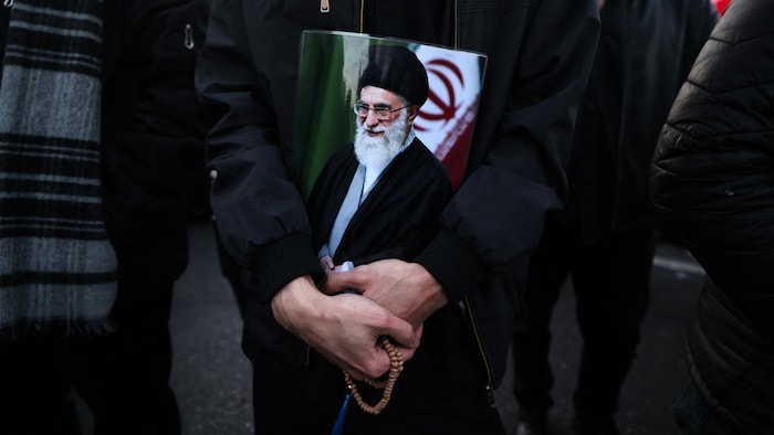 Un homme tient un portrait de l'ayatollah Ali Khamenei.