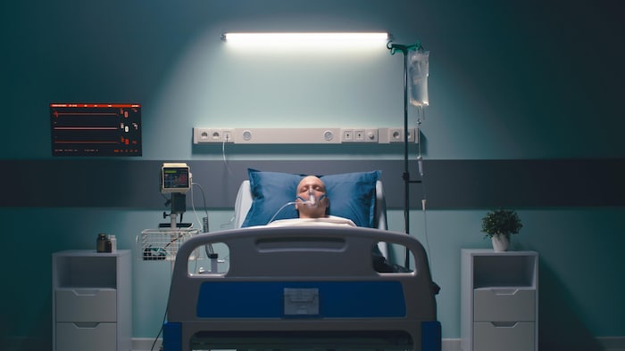 Un homme mort avec un masque à oxygène est allongé sur un lit d'hôpital.