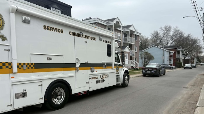 Une voiture de police de Trois-Rivières et le poste de commandement de la Sûreté du Québec sont stationnés devant un immeuble à logement.
