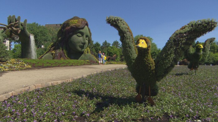 Une famille admire une des sculptures horticoles présentée dans le cadre des Mosaïcultures.