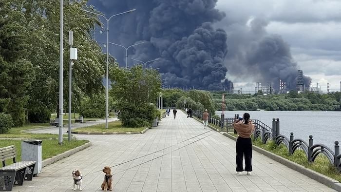Une femme prend une photo d'une colonne de fumée noire qui s'élève de Moscou.