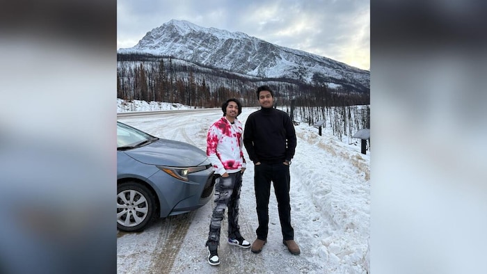 Les deux étudiants, un à côté de l'autre à côté d'une voiture.