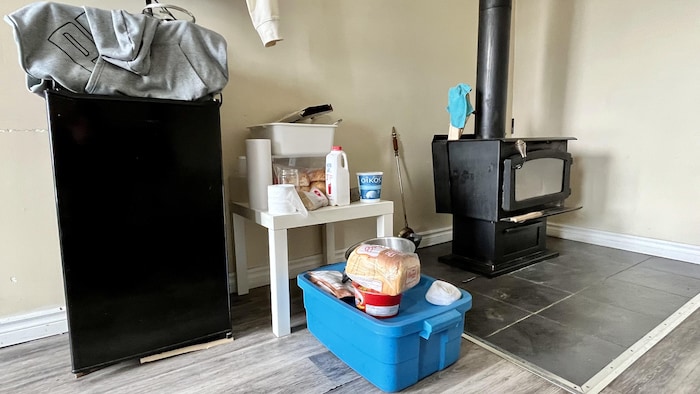 Un petit réfrigérateur, une table basse avec des aliments, une casserole. 
