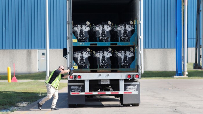 Un camionneur ferme la porte d'un camion-remorque transportant des moteurs fabriqués par le constructeur General Motors
