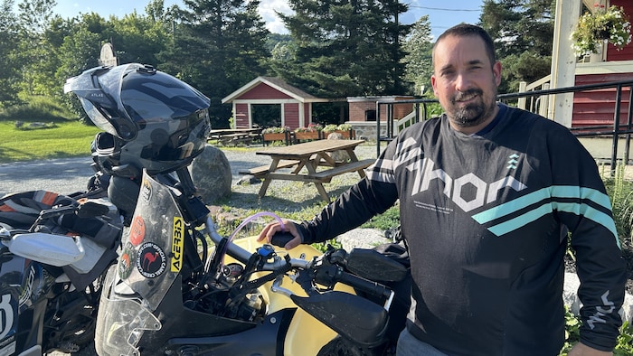 Un homme appuyé sur sa moto.
