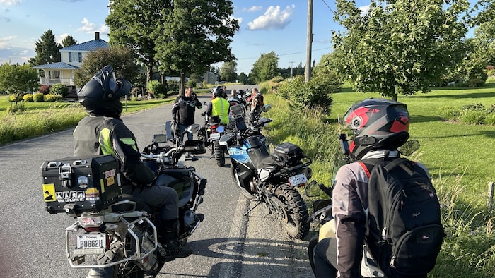 Des motocyclistes arrêtés en bordure d'une route.