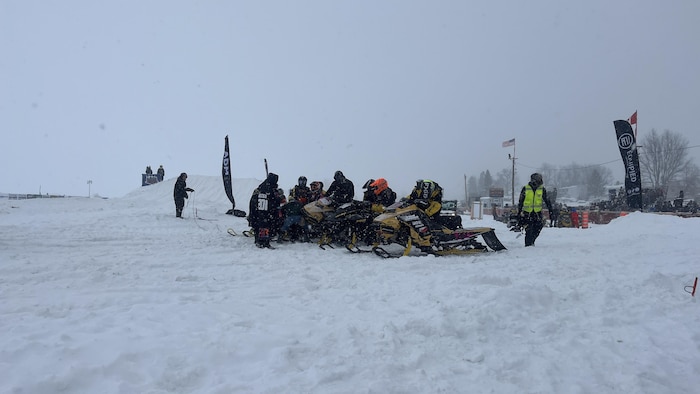 Des motoneigistes se préparent à participer à une course.