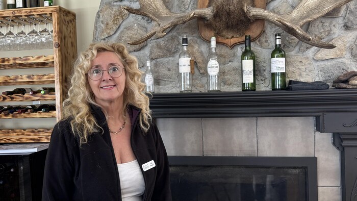 Une femme pose devant un foyer avec des bouteilles d'alcool.