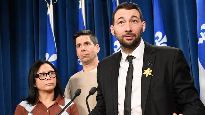 Il s'adresse aux médias derrière un lutrin muni de microphones.