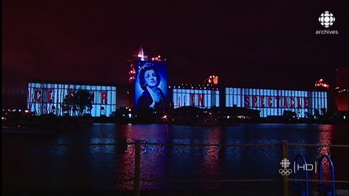 Les silos du bassin Louise dans le Vieux-Port de Québec sont illuminés avec l'image de la chanteuse Alys Robi et les mots « Ce soir en spectacle ». 