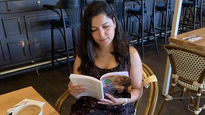 سلام شيّا تحمل كتابها في أحد المقاهي في مونتريال.