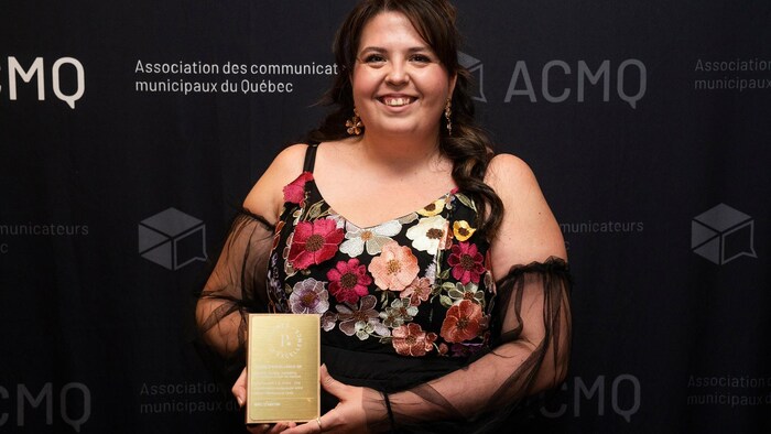 Roxanne Brousseau sourit à la caméra en montrant une plaque.