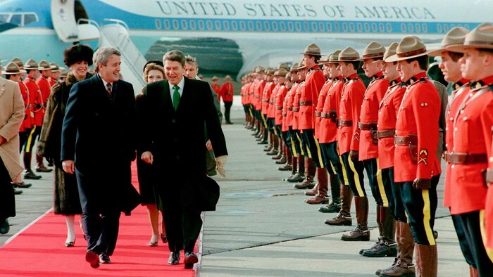 Le premier ministre canadien et le président américain marchent sur un tapis rouge devant des agents de la GRC.