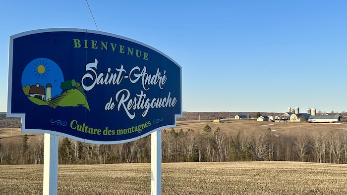 La pancarte annonçant Saint-André-de-Restigouche et derrière, des bâtiments de ferme