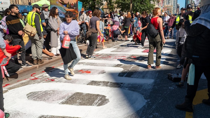Des manifestations peignent une murale sur la rue Wellington.