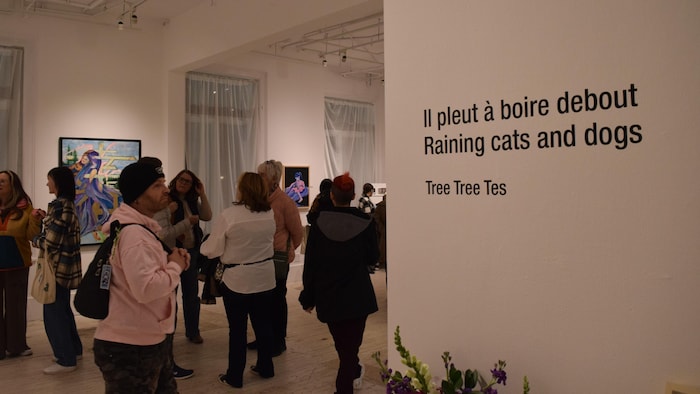 Des visiteurs qui regardent des œuvres exposées sur les murs d'une galerie.