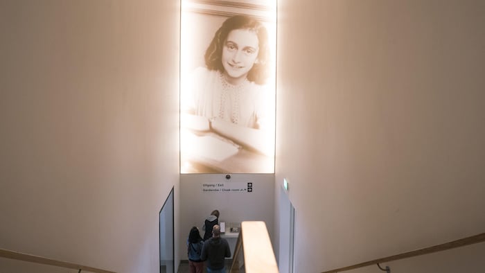 Du haut d'un escalier, on voit une photo d'Anne Frank.