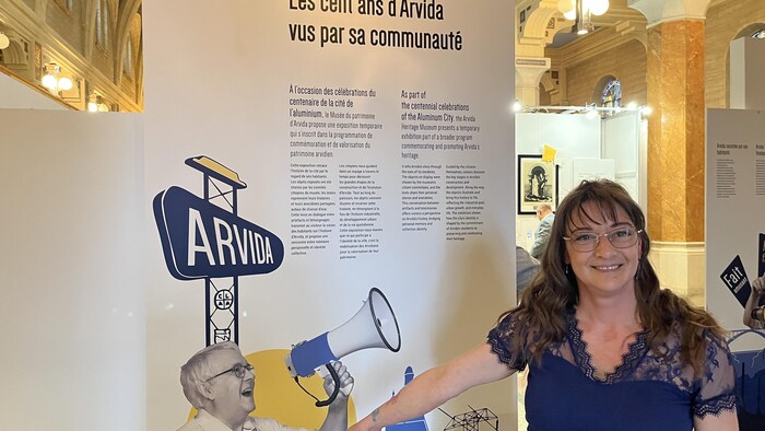Une femme prend la pose à côté d'une affiche. 