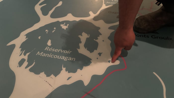 Une main pointe un point précis sur une carte au sol.