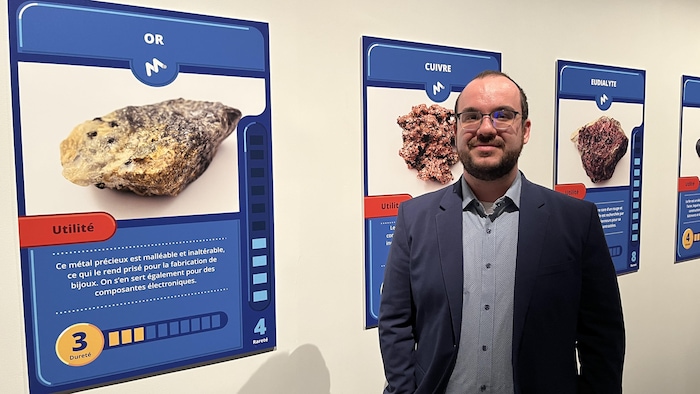 Maxime Bolduc pose devant certaines affiches de l'exposition Creuser les pixels.