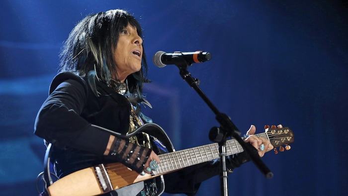 Une chanteuse avec sa guitare à la main.