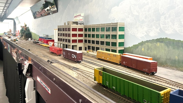 Une maquette de trains de marchandises du CN sur des rails, devant un bâtiment industriel.