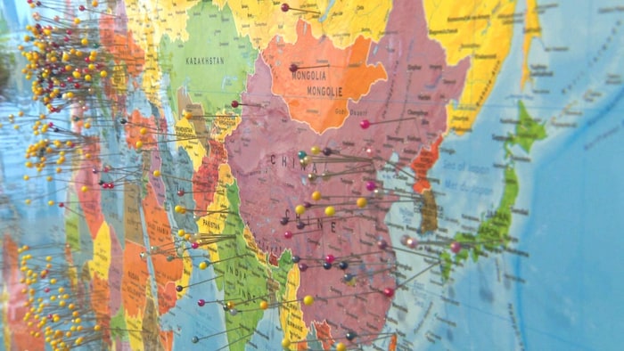 Une carte du monde photographiée à partir de la Chine et de la Mongolie, avec plusieurs épingles sur les pays.
