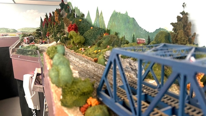 Une maquette de montagnes en automne, à laquelle mènent un pont de train et des rails.