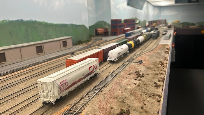 Des trains miniatures avec le logo du Canadien National et des wagons-citernes sur des rails.