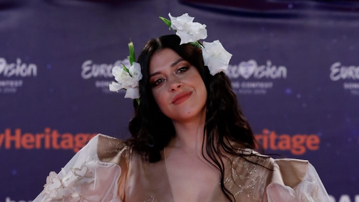 La chanteuse Katerine Duska vêtue d'une robe beige et portant trois fleurs blanches dans les cheveux.