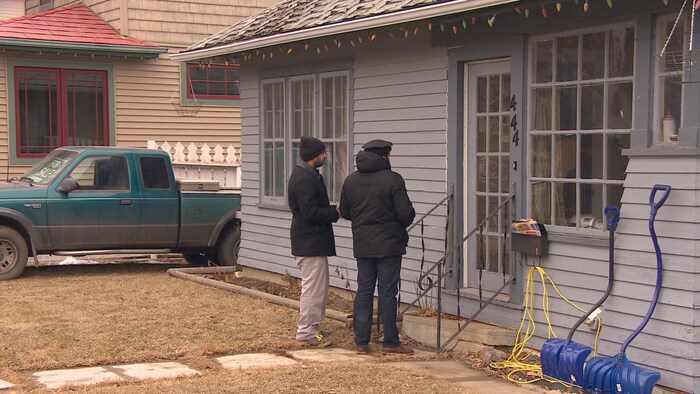 Des hommes se tiennent devant la porte d'une maison.