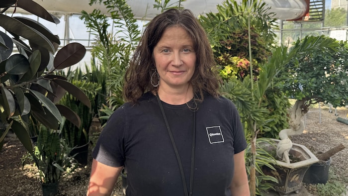 Kristal Forrest de face dans une serre, avec des plantes.