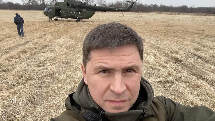 Self-portrait of Michelo Podoliak in a field, next to a helicopter.