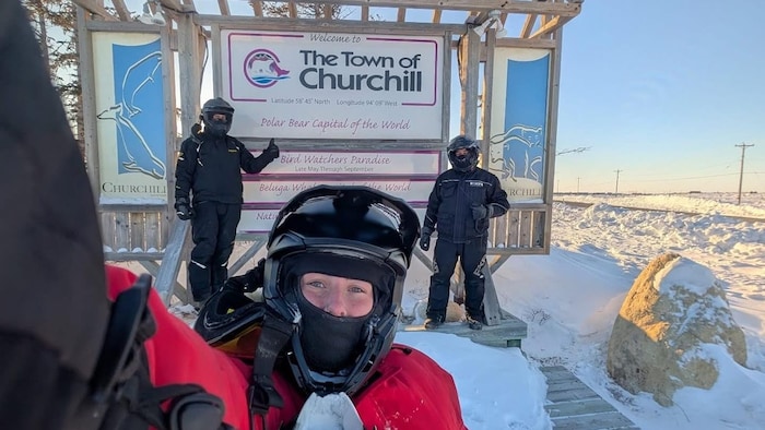 Trois individus devant la pancarte de Churchill, l'hiver.