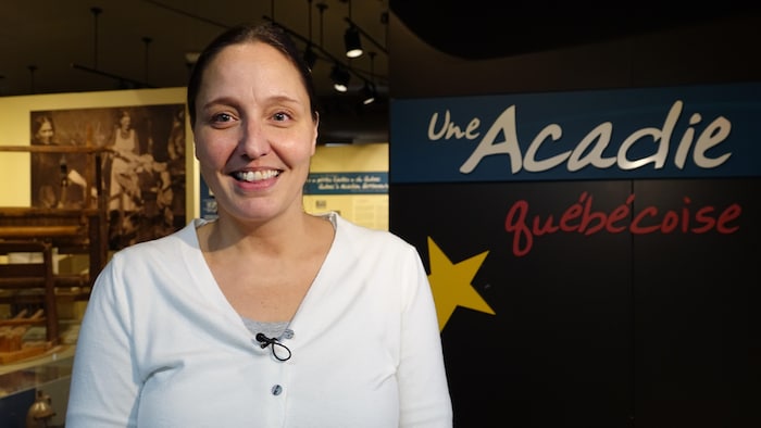 La directrice du musée, Myriam Custeau, est souriante devant une inscription «Une Acadie Québécoise».