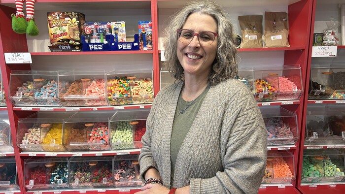 Myriam Ross sourit devant des rangées de bonbons.