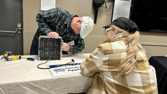 Myrna Lickiss qui regarde le réparateur qui essaie de réparer son grille-pain au Repair Cafe à Okotoks en mars 2023.