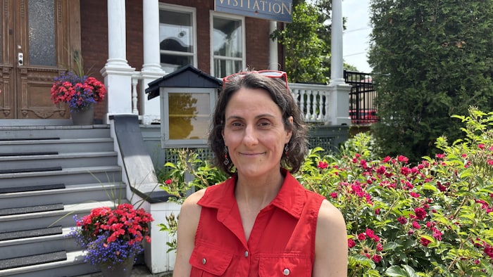 Une femme devant une auberge fleurie.