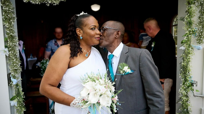 Un homme embrasse sa femme sur la joue le jour de leur mariage.