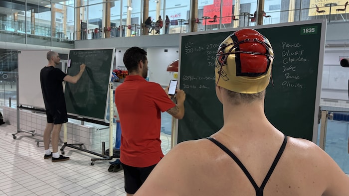 Une nageuse avec un casque de bain qui regarde un tableau.