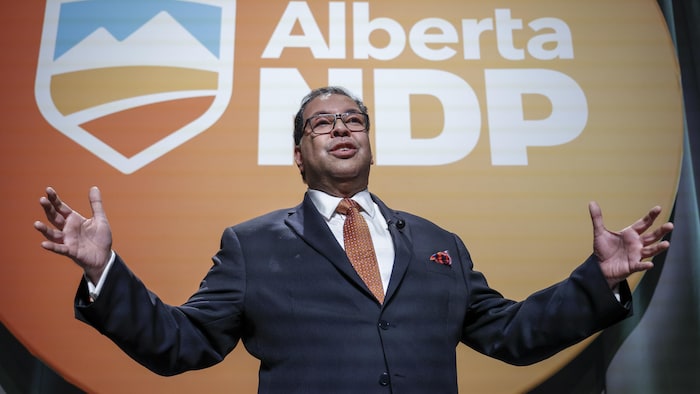 Un homme devant le logo du NPD de l'Alberta. 22 juin 2024.