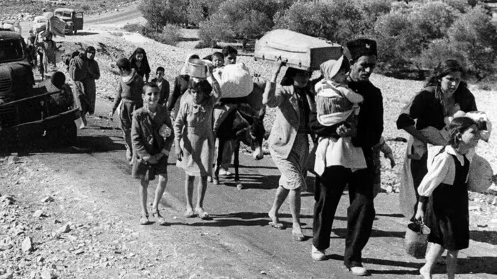 Un groupe de réfugiés marche en portant leurs possessions.