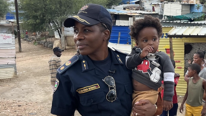 Une policière avec un enfant dans les bras.  
