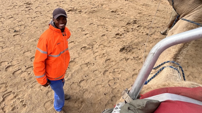 Un homme devant un dromadaire. 