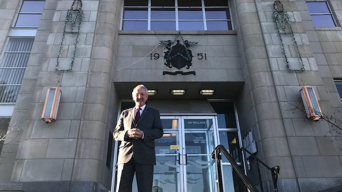 Portrait du maire devant l'hôtel de ville.