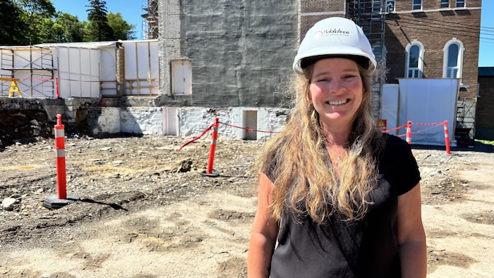 Nancy Belleau sourit à la caméra devant le chantier du monastère Sainte-Claire de Rivière-du-Loup