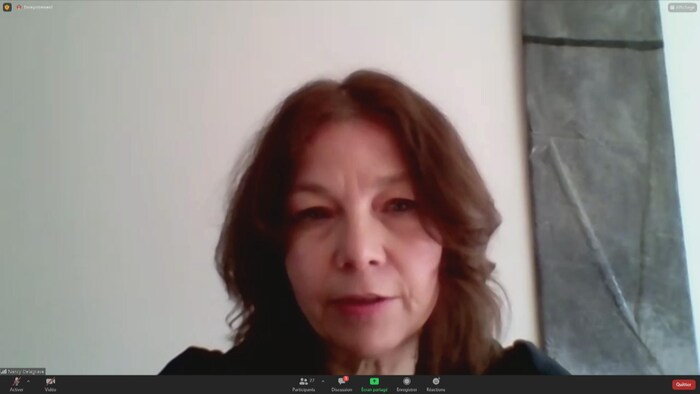 Nancy Delagrave parle devant un mur blanc.