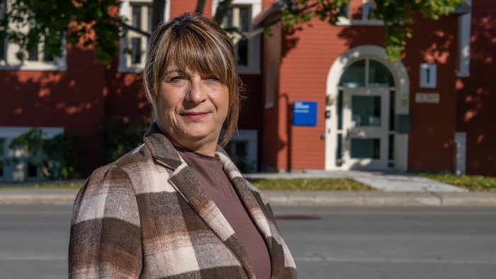 Portrait de la présidente devant le bureau de l'organisme scolaire.