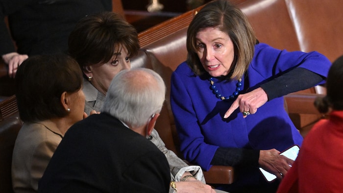 Nancy Pelosi sits and talks with three people.