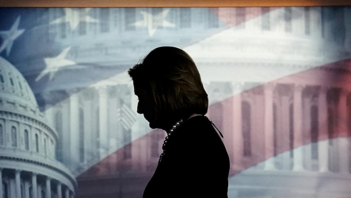 Mme Pelosi est photographiée à contre-jour devant un drapeau américain à l'arrière-plan sur un écran.